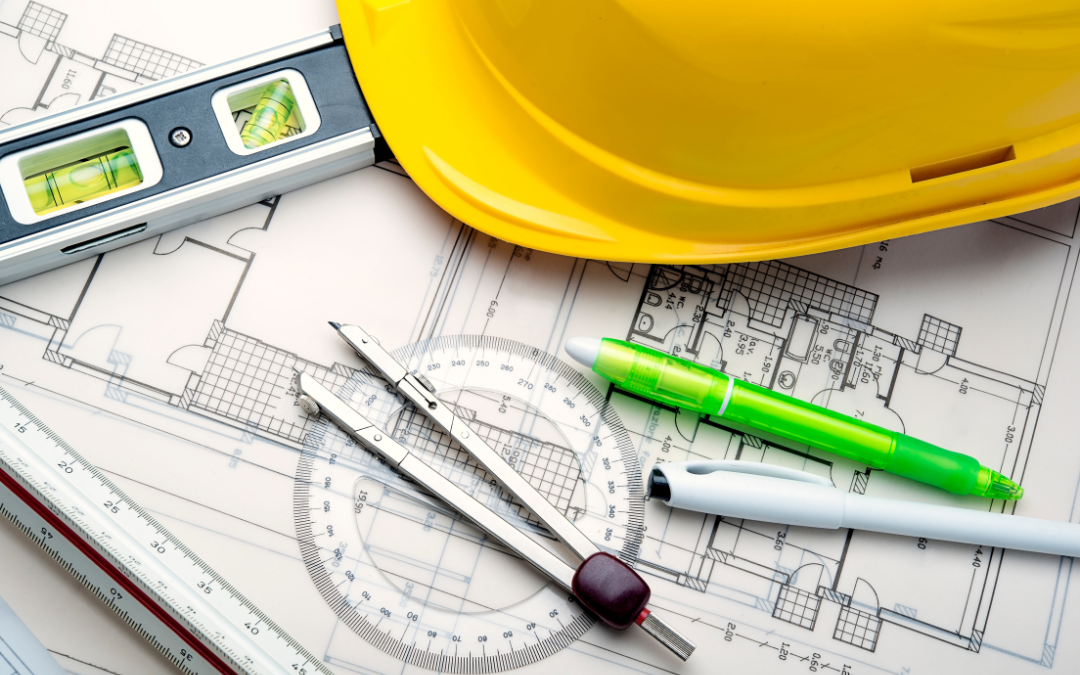 Yellow hard hat, scale and ruler sitting on retail construction blueprints